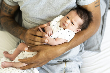 Porträt eines neugeborenen Babys in den Armen des Vaters im Bett - ERRF01315