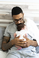 Father holding his newborn baby in bed - ERRF01318