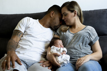 Parents cuddling with newborn baby on couch - ERRF01331