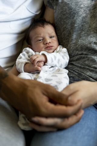 Porträt eines neugeborenen Babys zwischen seinen Eltern, lizenzfreies Stockfoto