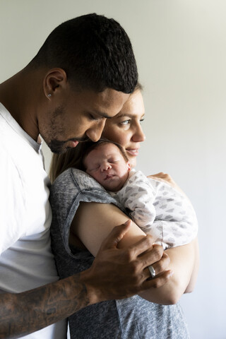 Parents cuddling with sleeping newborn baby stock photo