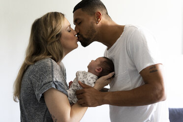 Küssende Eltern, die ihr neugeborenes Baby zu Hause halten - ERRF01344