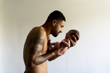 Zärtlicher Vater hält sein weinendes nacktes Neugeborenes - ERRF01354