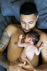 Father lying on couch with nude newborn baby - ERRF01357