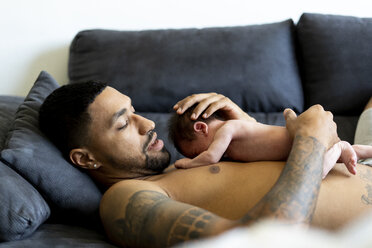 Father lying on couch with nude newborn baby - ERRF01358