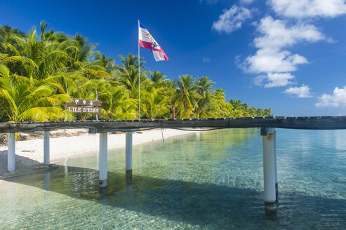 French Polynesia, Tuamotus, Tikehau, pier at palm beach with flag - RUNF02073