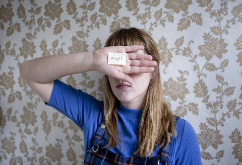 Student holding a hand in front of her eyes, a note with the word fear on her hand - FLLF00182