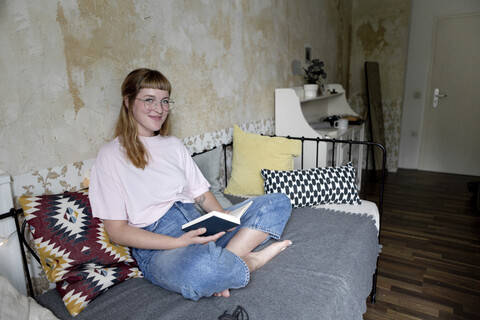 Studentin liest ein Buch in ihrem Zimmer, lizenzfreies Stockfoto