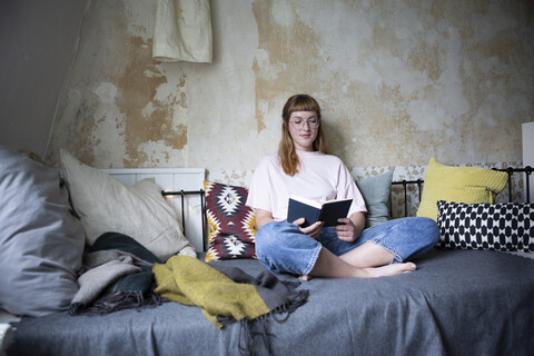 Studentin liest ein Buch in ihrem Zimmer, lizenzfreies Stockfoto