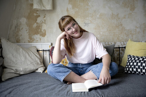 Female student reading a book in her room - FLLF00199