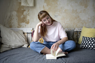 Female student reading a book in her room - FLLF00200