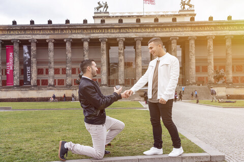 Junger Mann macht seinem überraschten Freund einen Heiratsantrag im Lustgarten, Berlin, Deutschland, lizenzfreies Stockfoto