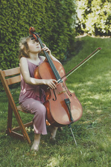 Ein Mädchen spielt Cello mit geschlossenen Augen im Garten - IHF00024