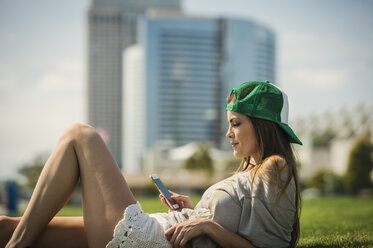 Caucasian woman laying in grass texting on cell phone - BLEF03686