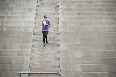 Caucasian woman running on stadium staircase - BLEF03692