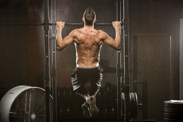 Caucasian man doing chin-up in gymnasium - BLEF03726