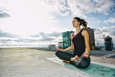 Caucasian woman meditating on urban rooftop - BLEF03832