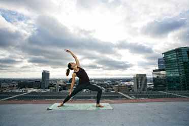 Caucasian woman stretching on urban rooftop - BLEF03834