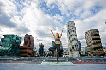 Kaukasische Frau macht Yoga auf dem Dach einer Stadt - BLEF03835