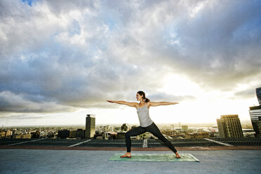 Caucasian woman stretching on urban rooftop - BLEF03847