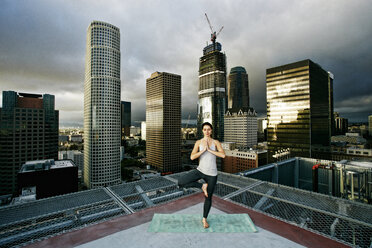 Caucasian woman doing yoga urban rooftop - BLEF03849