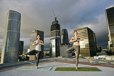 Caucasian women doing yoga urban rooftop - BLEF03850