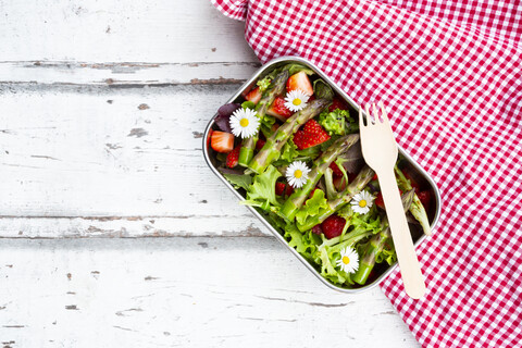 Lunchbox mit grünem Salat, grünem Spargel, Erdbeeren und Gänseblümchen, lizenzfreies Stockfoto