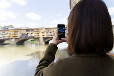 Italien, Florenz, junge Touristin, die ein Handyfoto am Ponte Vecchio macht - FMOF00626