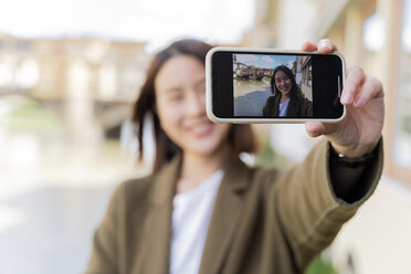Italien, Florenz, junge Touristin, die ein Selfie am Ponte Vecchio macht - FMOF00627