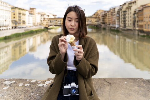 Italien, Florenz, junge Touristin isst eine Eistüte auf der Ponte Vecchio, lizenzfreies Stockfoto