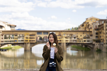 Italy, Florence, young tourist woman eating an ice cream cone at at Ponte Vecchio - FMOF00637