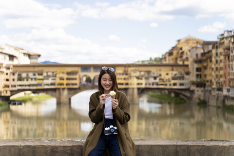 Italy, Florence, young tourist woman eating an ice cream cone at at Ponte Vecchio stock photo