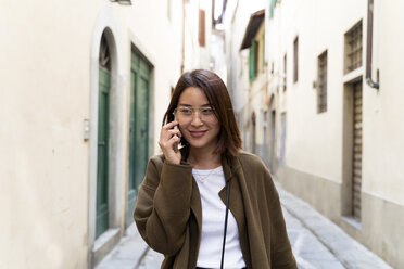 Italien, Florenz, junge Frau am Handy in einer Gasse - FMOF00646