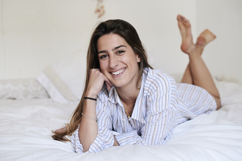 Lächelnde Frau auf dem Bett liegend, lizenzfreies Stockfoto