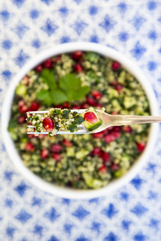 Bulgur herbs tabbouleh with pomegranate seeds on fork, close-up stock photo