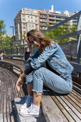 Junge Frau sitzt auf einer Bank in Barcelona - AFVF02943