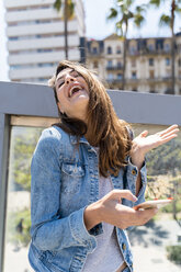 Young woman laughing while using smartphone in Barcelona - AFVF02948