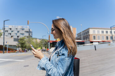 Junge Frau mit Smartphone auf einer Fußgängerbrücke in Barcelona - AFVF02956