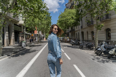 Junge Frau, die in Barcelona auf einer Straße geht und zurückblickt - AFVF02966
