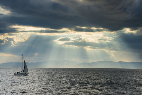 Segelboot vor dem Durchbruch der Sonne durch die Wolken über dem Amur in Wladiwostok, Russland - RUNF02098