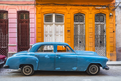 Geparkter blauer Oldtimer vor einem Wohnhaus, Havanna, Kuba, lizenzfreies Stockfoto