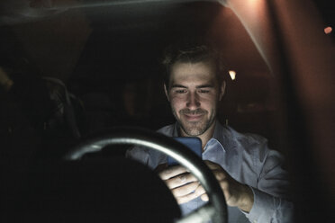 Young man using cell phone in car at night - UUF17606