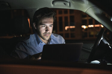 Junger Mann benutzt Laptop im Auto bei Nacht - UUF17608