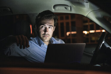 Junger Mann mit Laptop im Auto bei Nacht - UUF17609