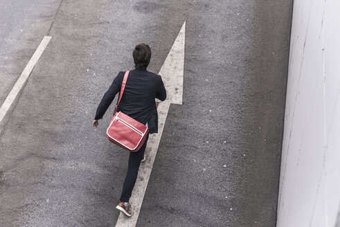 Rear view of businessman running on road with arrow sign - UUF17630