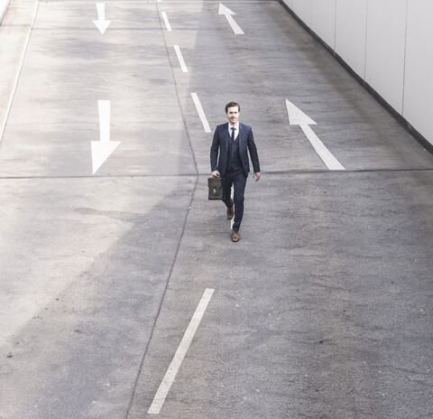 Geschäftsmann zu Fuß auf Straße mit Pfeilzeichen, lizenzfreies Stockfoto