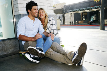 Caucasian couple sitting on sidewalk - BLEF03913