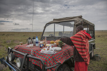 Schwarzer Mann beim Picknick auf der Motorhaube eines Autos in einem abgelegenen Feld - BLEF03925