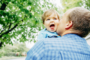 Vater küsst Wange seines kleinen Sohnes im Freien - BLEF03969