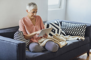 Ältere kaukasische Frau mit digitalem Tablet auf dem Sofa - BLEF03983